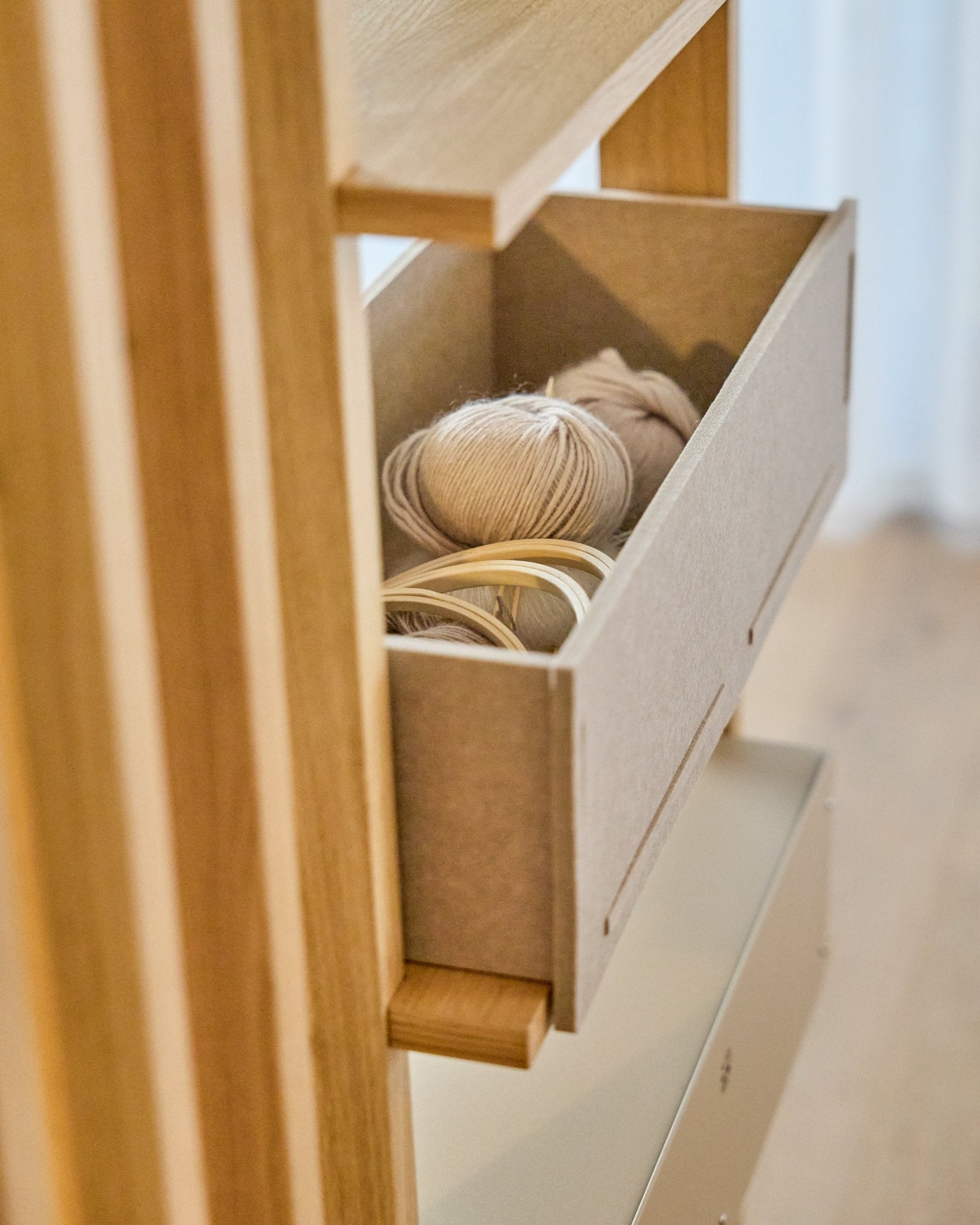 WoodUpp Vigg Felt Box / BM2 i beige rymmer lätta garnnystan och broderiringar i trä på en trähylla och kompletterar nordiska akustikpaneler.